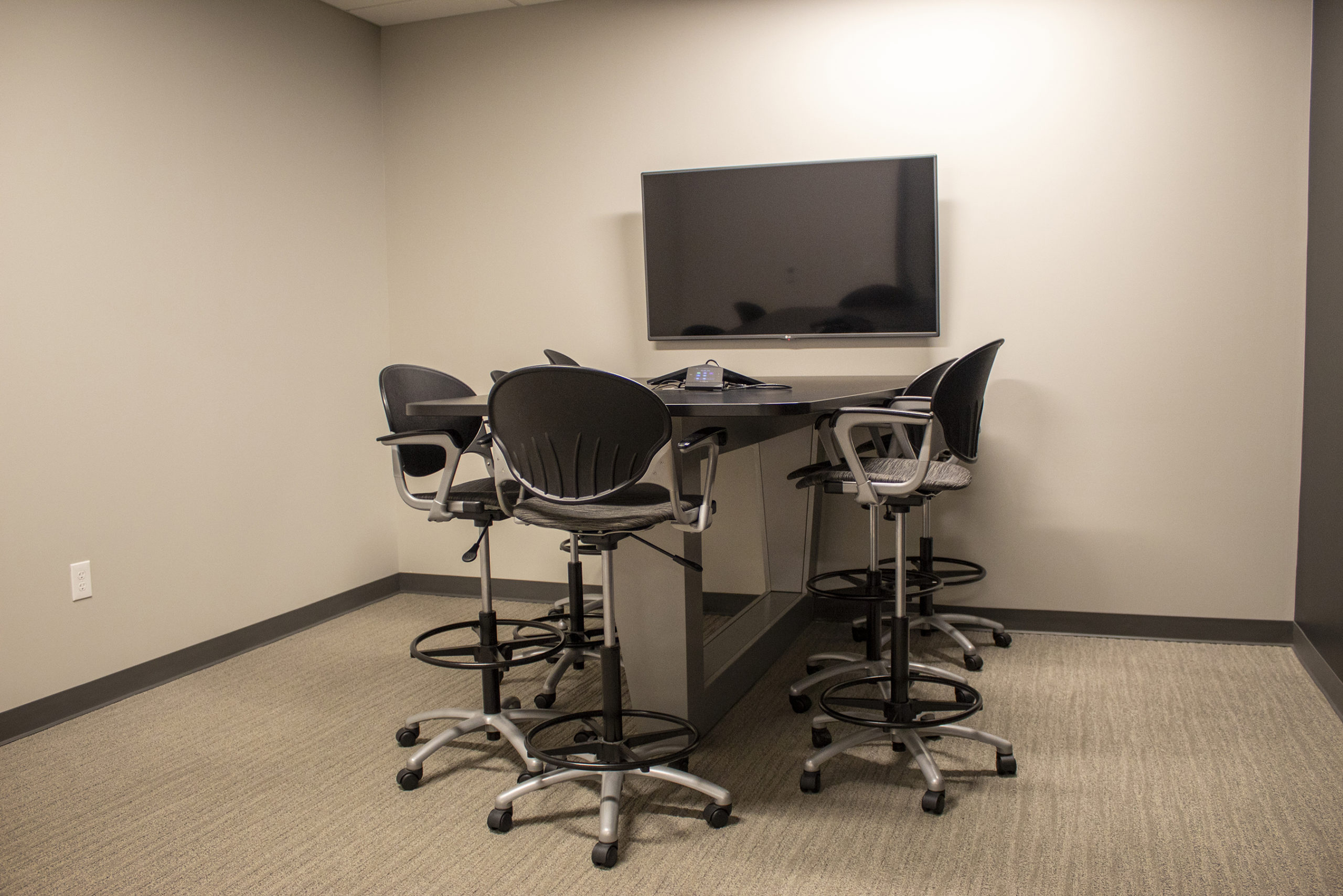 small conference room with standing height table and chairs and media center